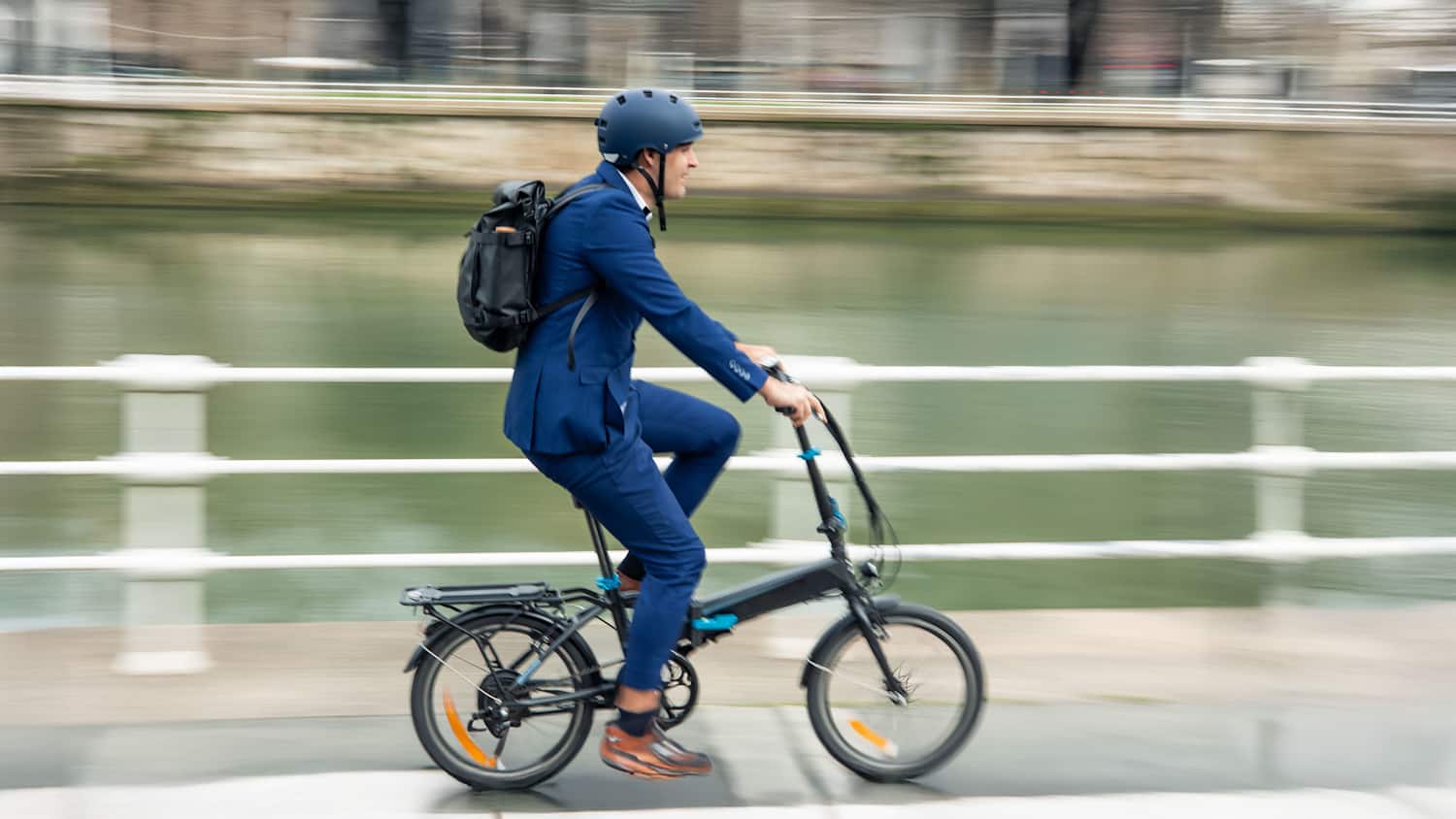 Eine dynamische Aufnahme, die die Bewegung eines Geschäftsmannes einfängt, der mit seinem Elektrofahrrad durch die Stadt pendelt und so für nachhaltige Fortbewegung wirbt
