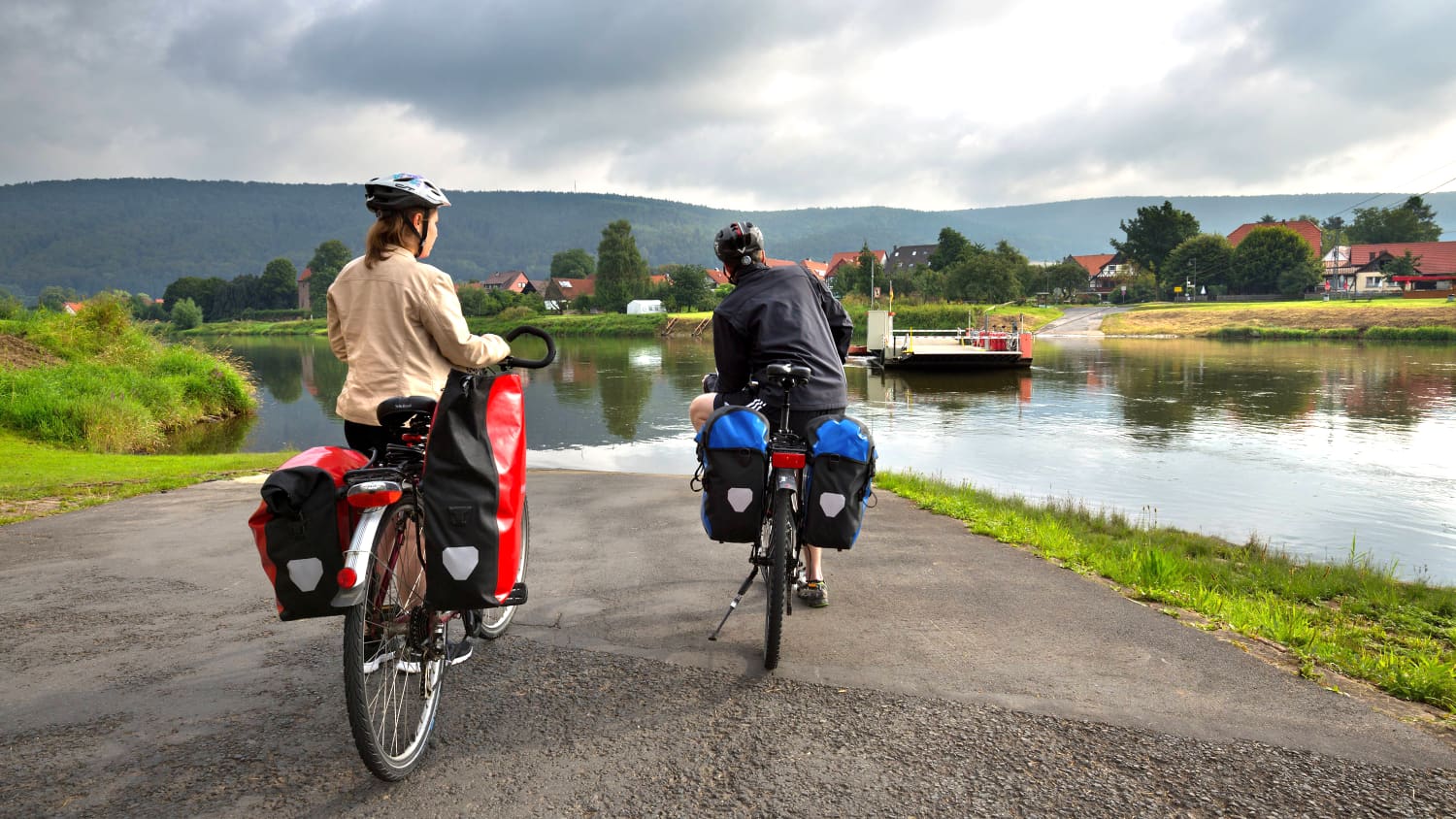 Fahrradfahrer warten an einem Fluss auf eine Fähre