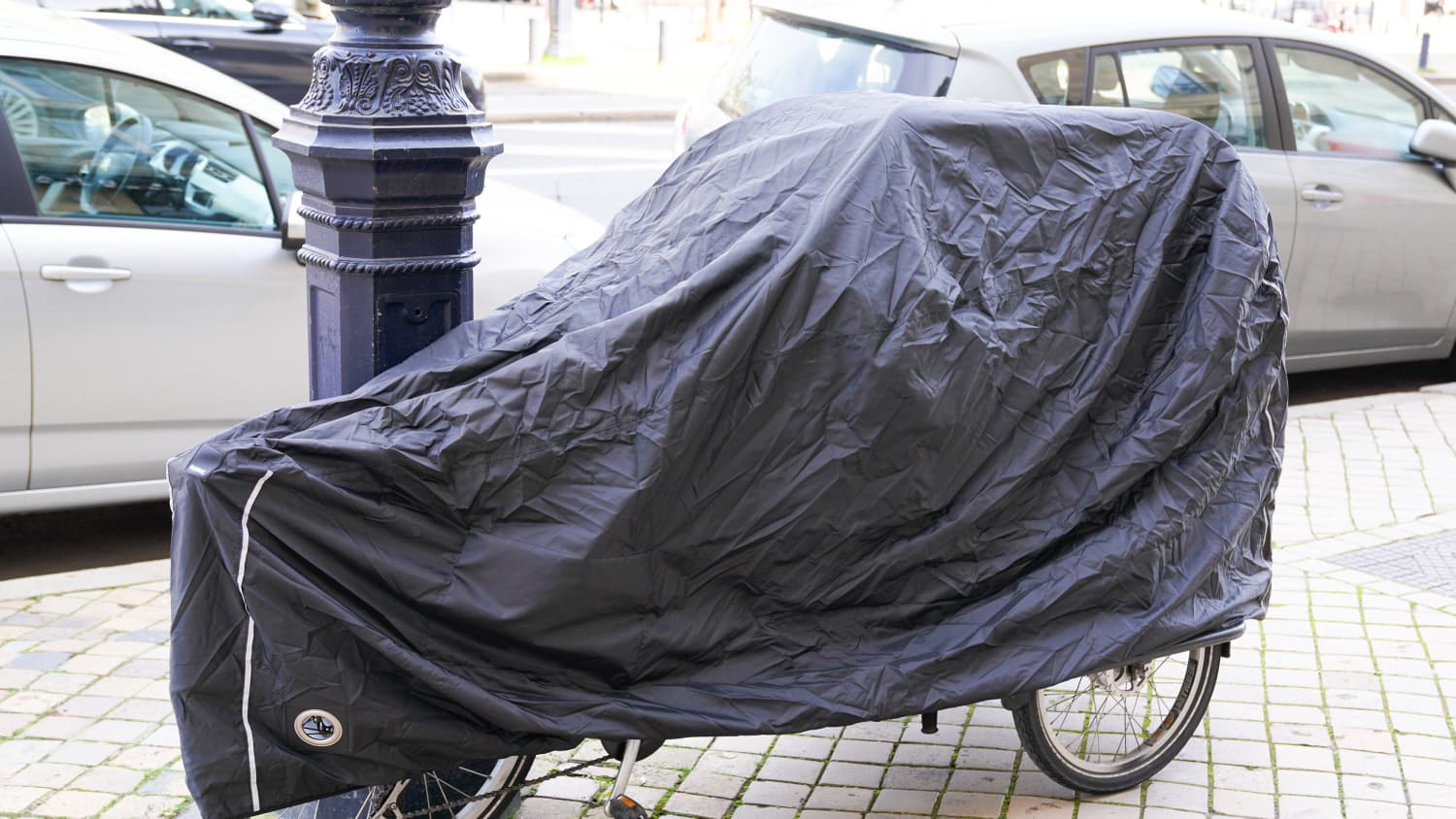 Angeperrtes Fahrrad in der Stadt mit einer Abdeckplane