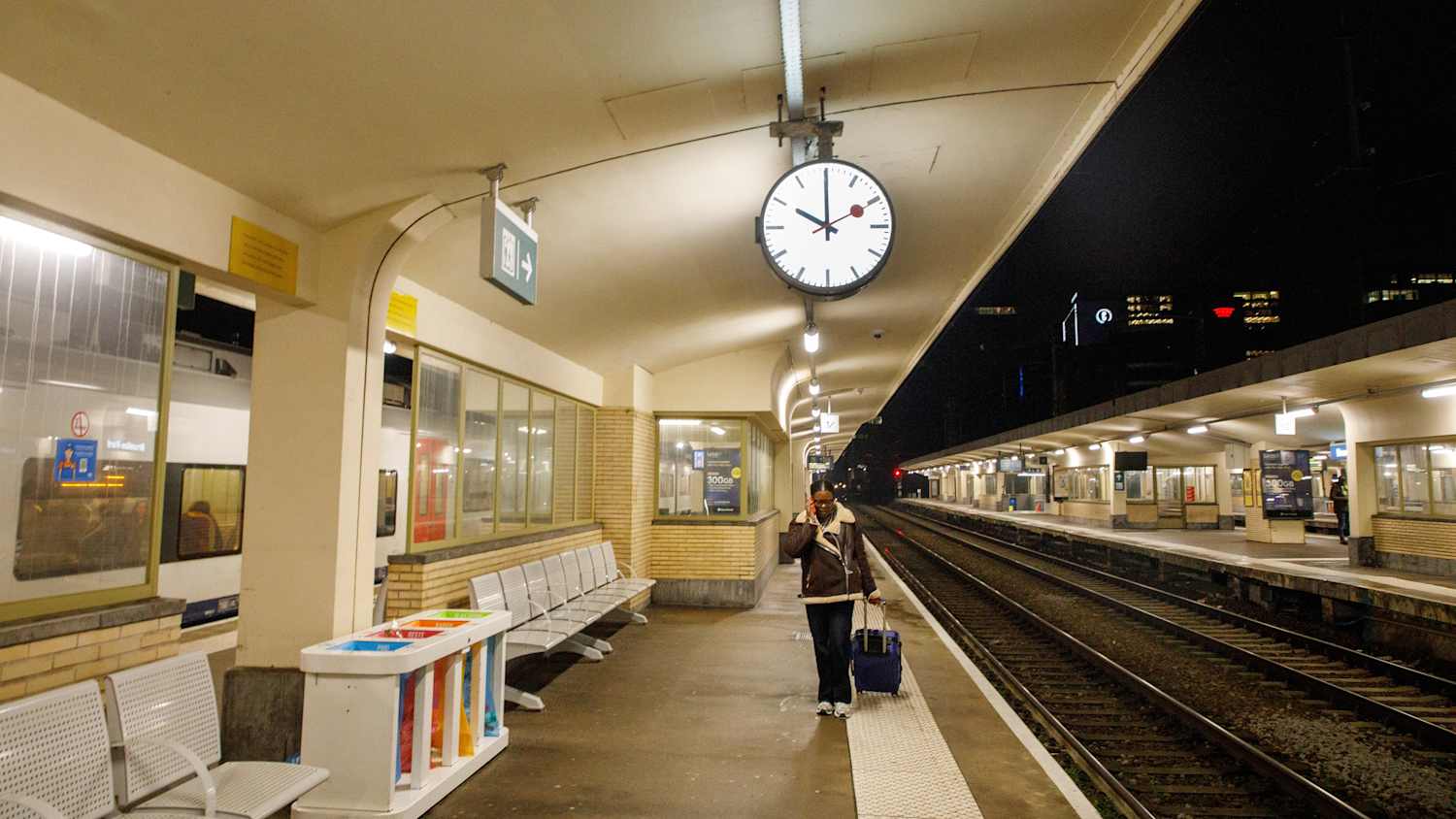 Eine Frau mit Rollkoffer an einem Bahnhof in Belgien