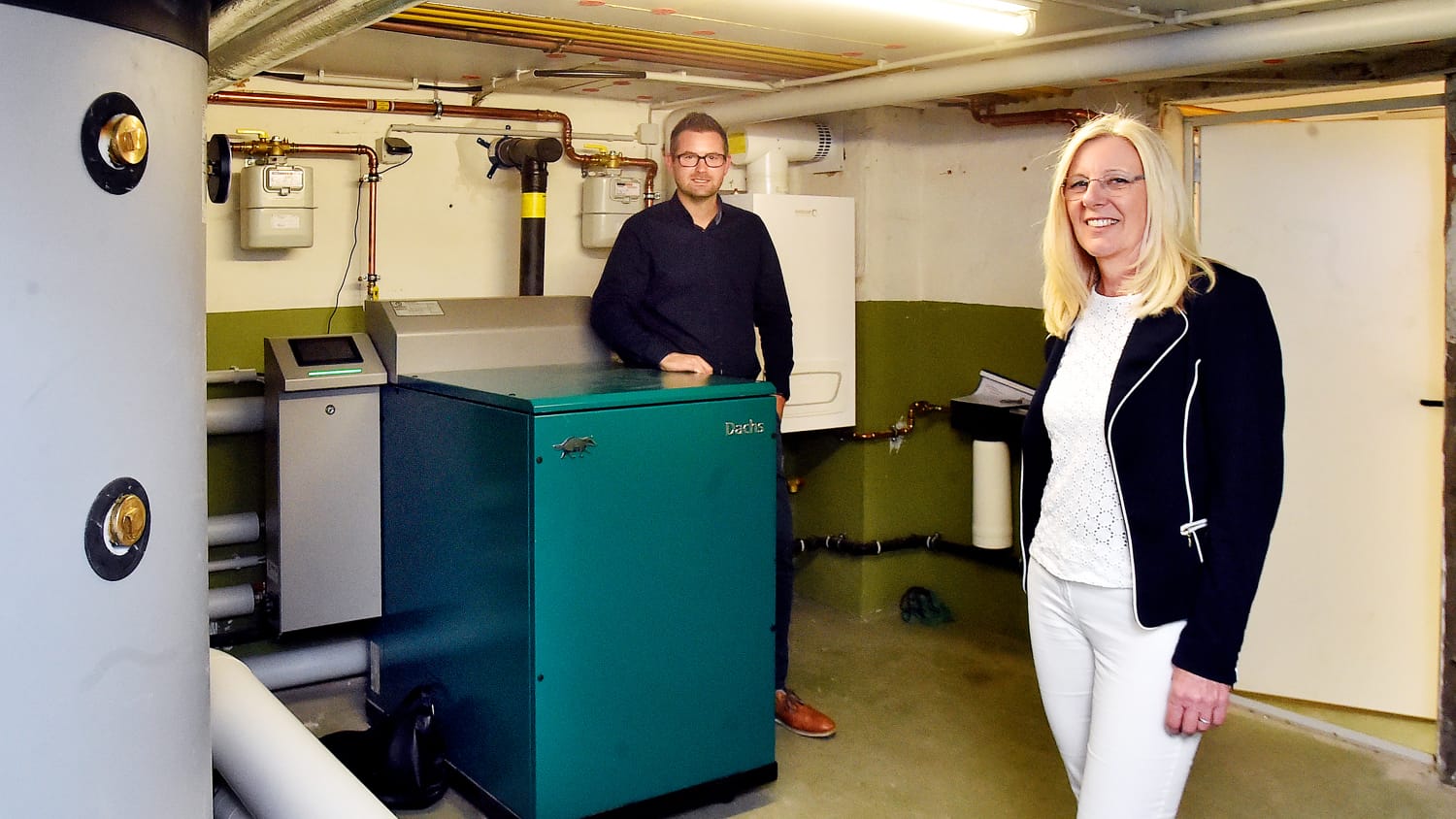 Ein Blockheizkrafterk im Keller eines Einfamilienhauses wessen Besitzer glücklich davor stehen