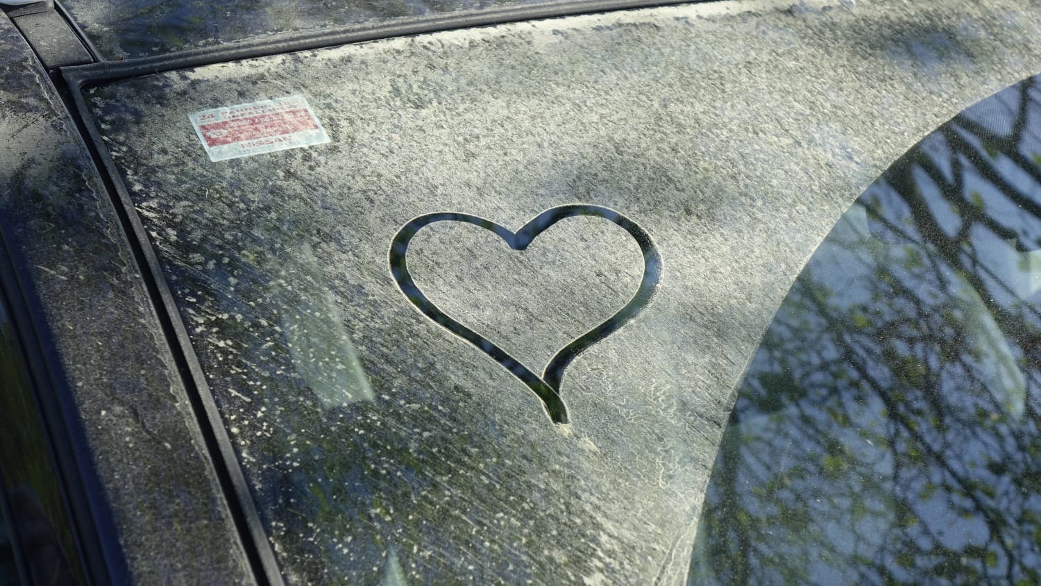 Ein Herz das in den Blütenstaub auf einer Windschutzscheibe gemalt ist
