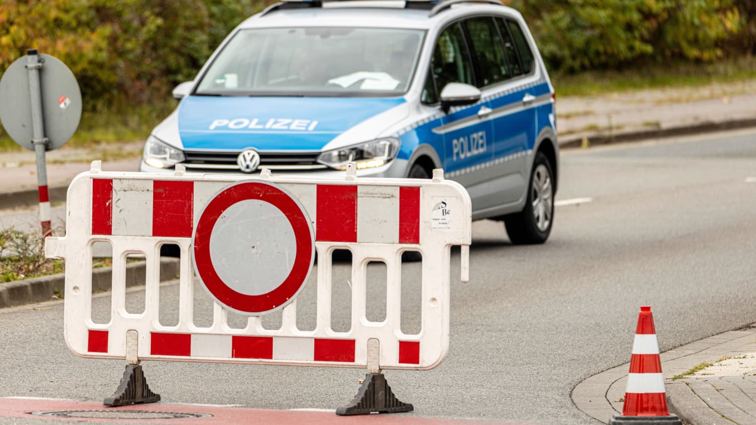 Ein Einsatzfahrzeug der Polizei mit Blaulicht und Schriftzug hinter einer Absperrung