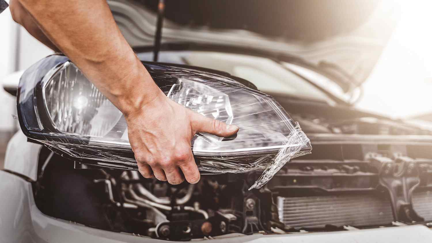 Ein Mechaniker baut einen neuen Scheinwerfer an einem Auto ein