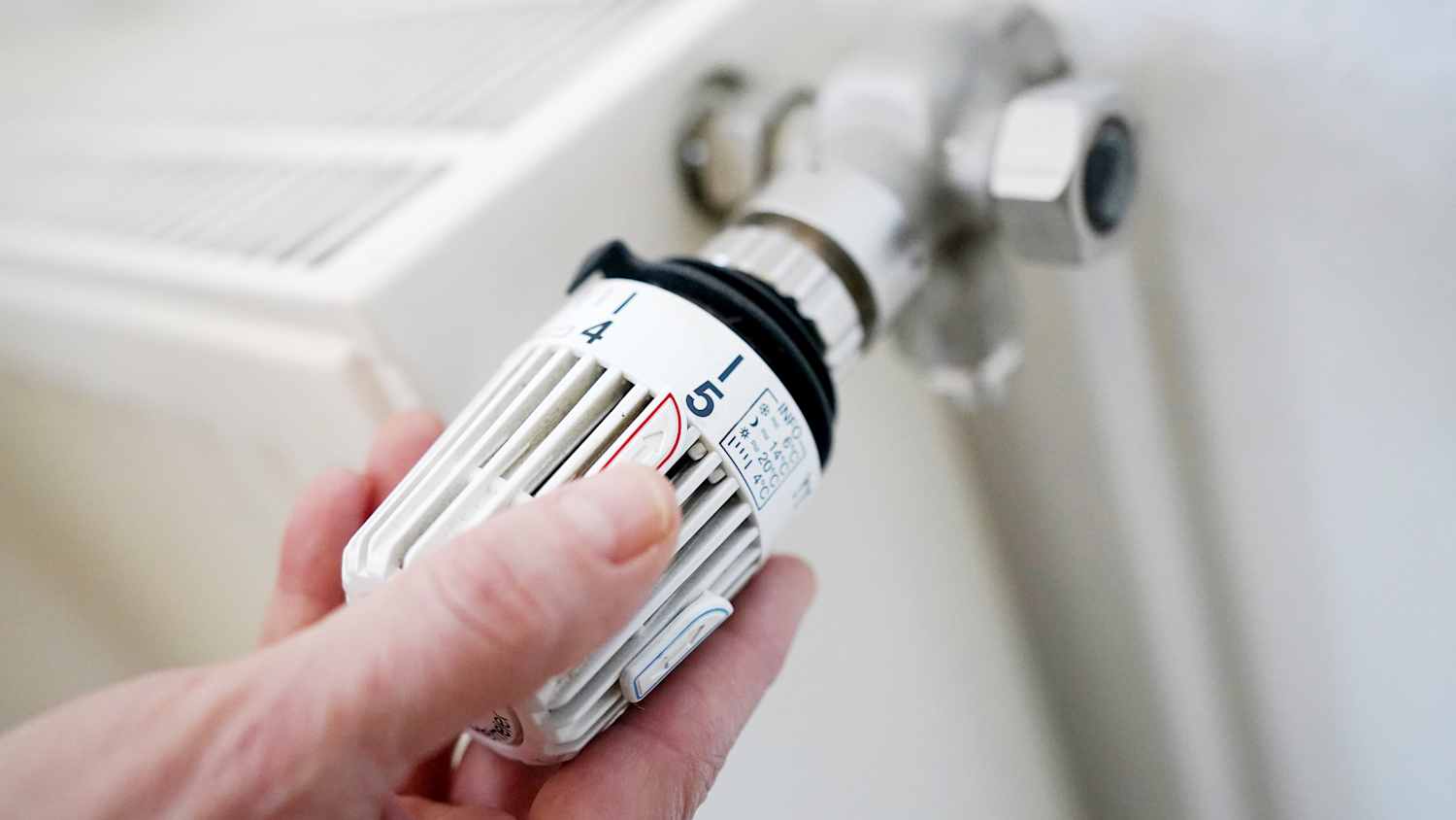 Eine Hand die an einem Heizungsthermometer dreht