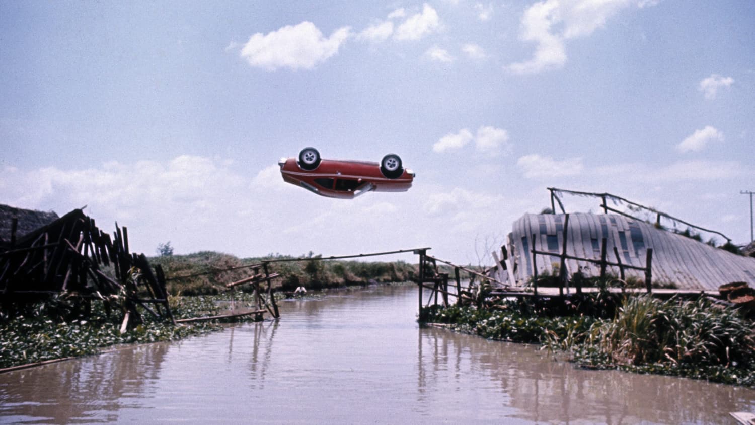 Ein Auto fliegt Kopf über in der Luft über einen Fluss