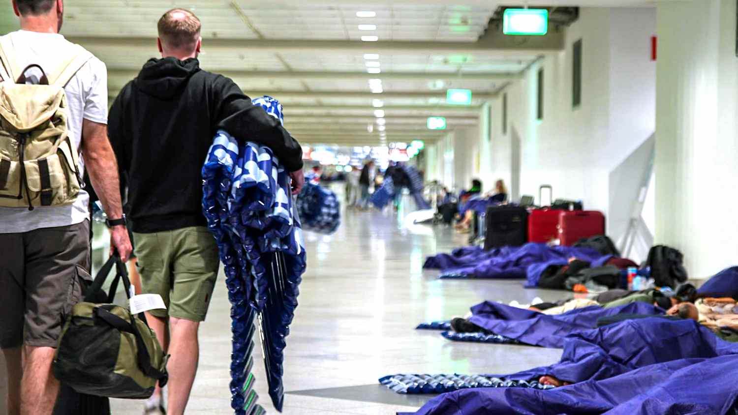 Menschen ruhen sich nach möglichen Drohnensichtungen am Flughafen München aus. Der Flughafen München hat am Abend wegen möglicher neuer Drohnen-Sichtungen wieder den Betrieb eingestellt.