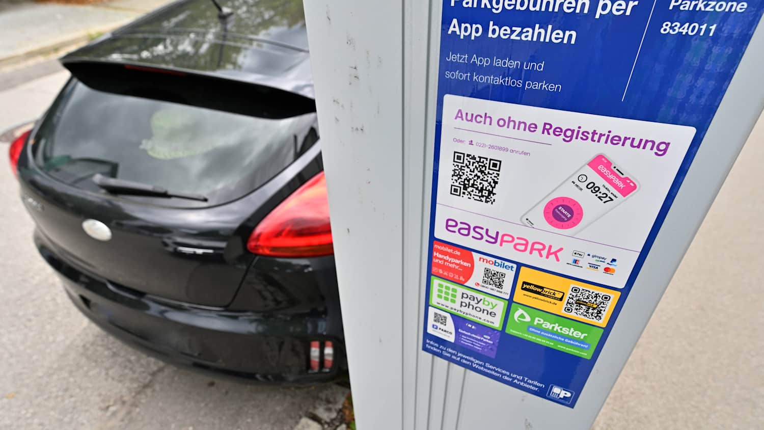 Am Straßenrand in der Innenstadt steht ein Parkscheinautomat. Im Hintergrund parkt ein Auto