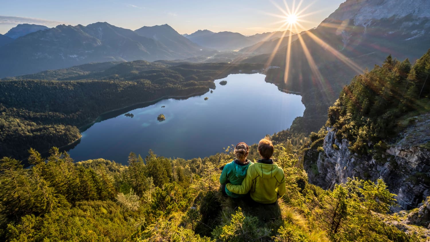 Pärchen sitzt auf einem Felsvorsprung und blickt auf den Eibsee