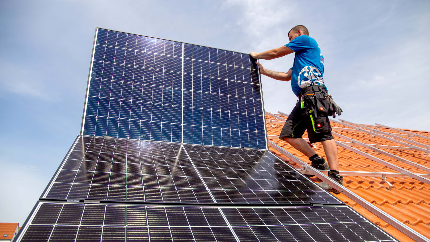 Ein Mann installiert eine Solaranlage auf einem Dach