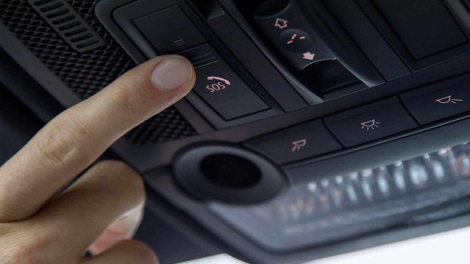 Clopse up Aufnahme eines Fingers, welcher den SOS Knopf im Auto betätigt.