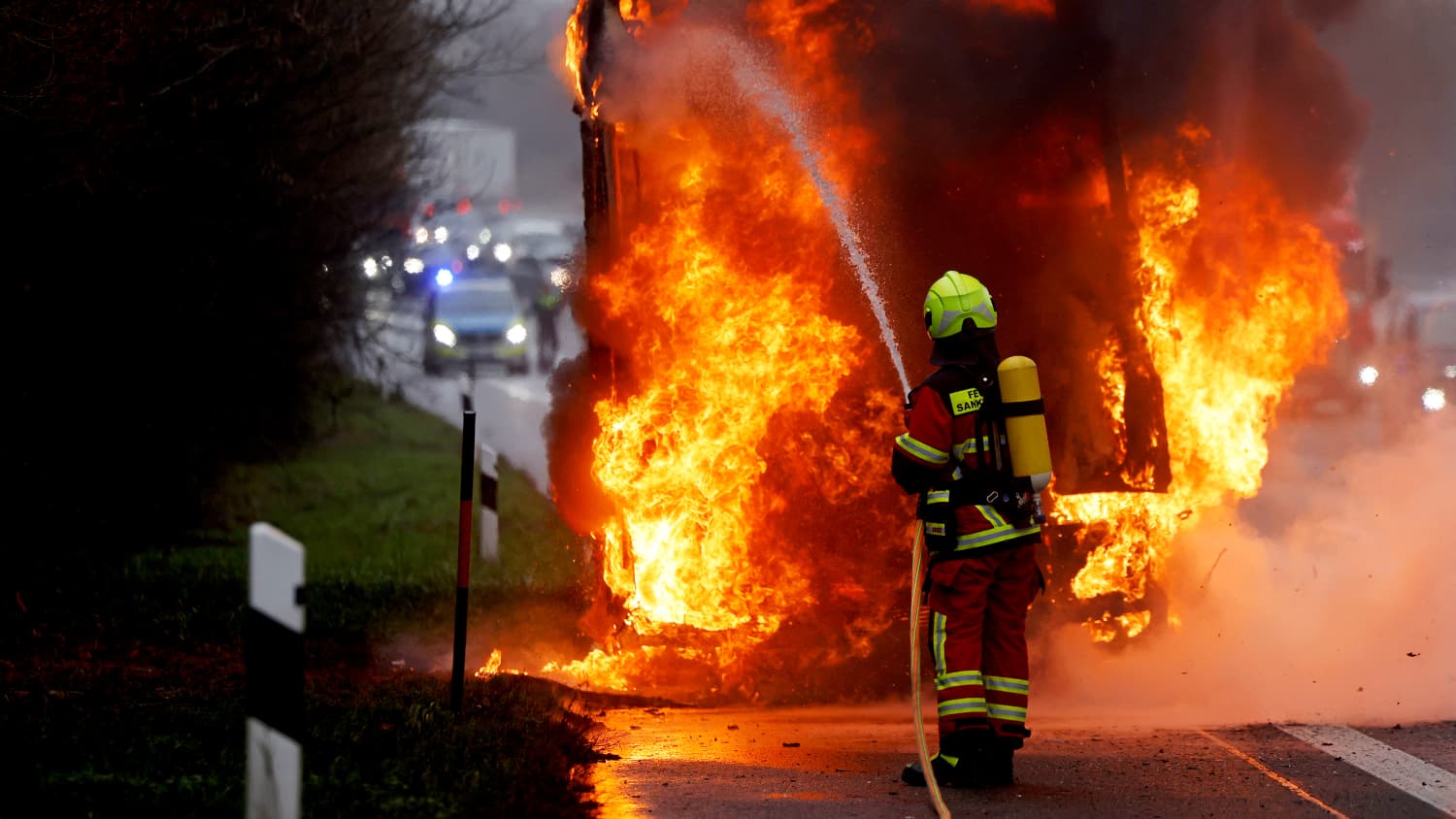 Eine Feuerwehrmann löscht auf der Autobahn das Feuer eines explodierten Lasters