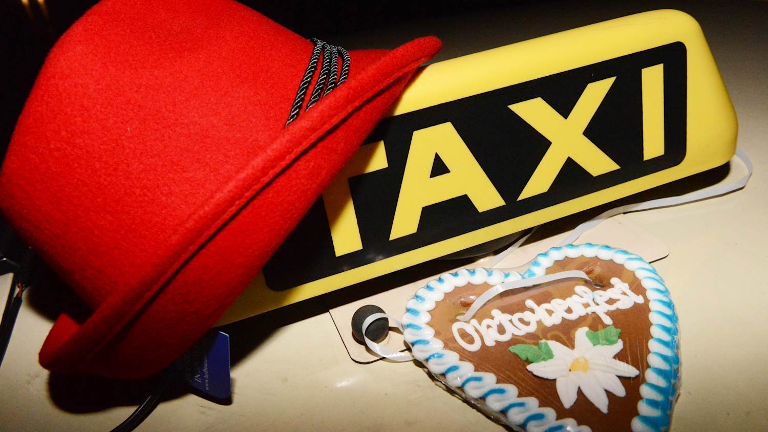 Ein roter Trachenhut und ein Lebkuchenherz liegen an einem Taxischild