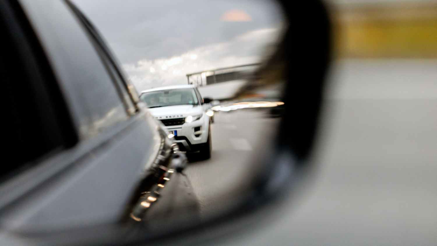 Ein dicht auffahrendes Auto auf der Autobahn ist im Außenspiegel zu sehen.