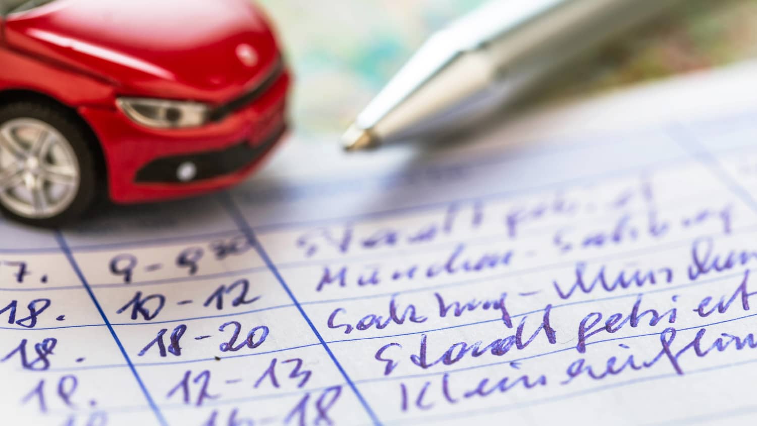 Ein Fahrtenbuch liegt mit einem Stift auf dem Tisch