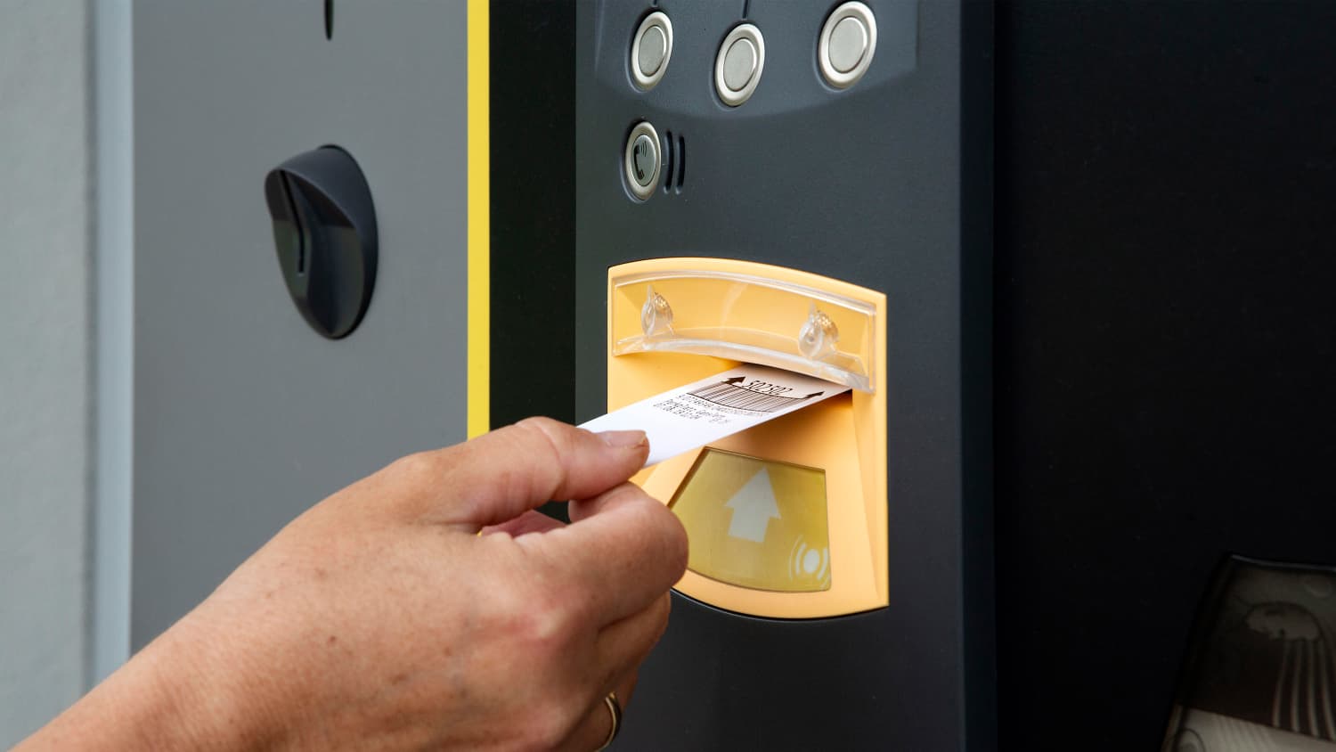 Eine Hand die gerade das Parkticket einführt