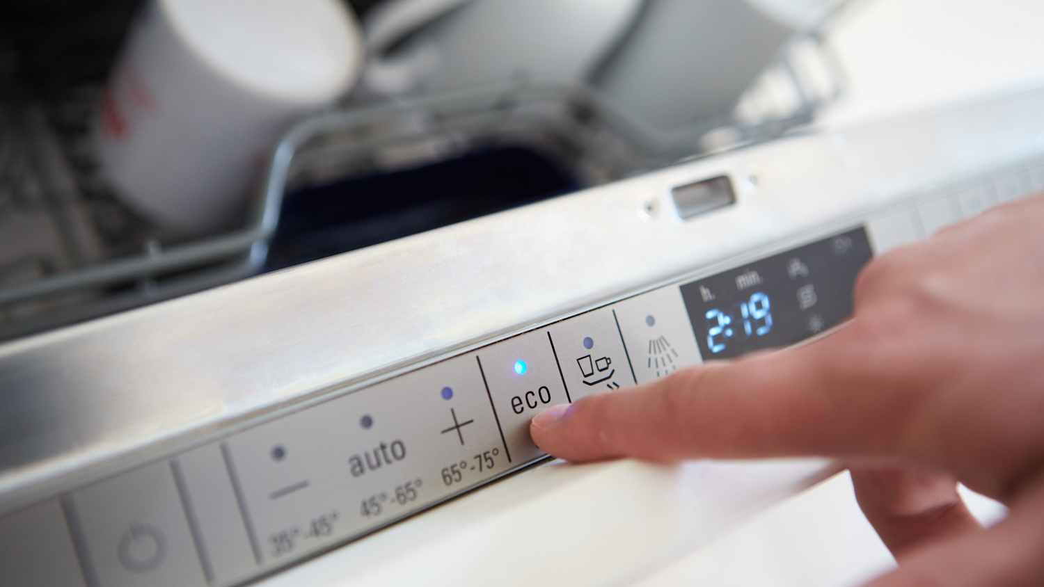 Eine Hand bedient die Eco-Taste der Spülmaschine