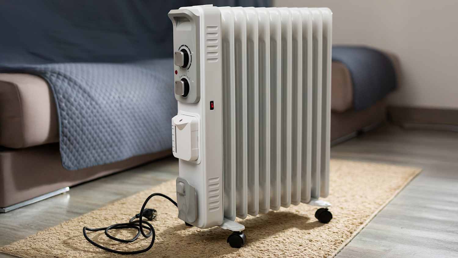 Öl-Radiator-Heizung steht auf einem Teppich vor einem Sofa.