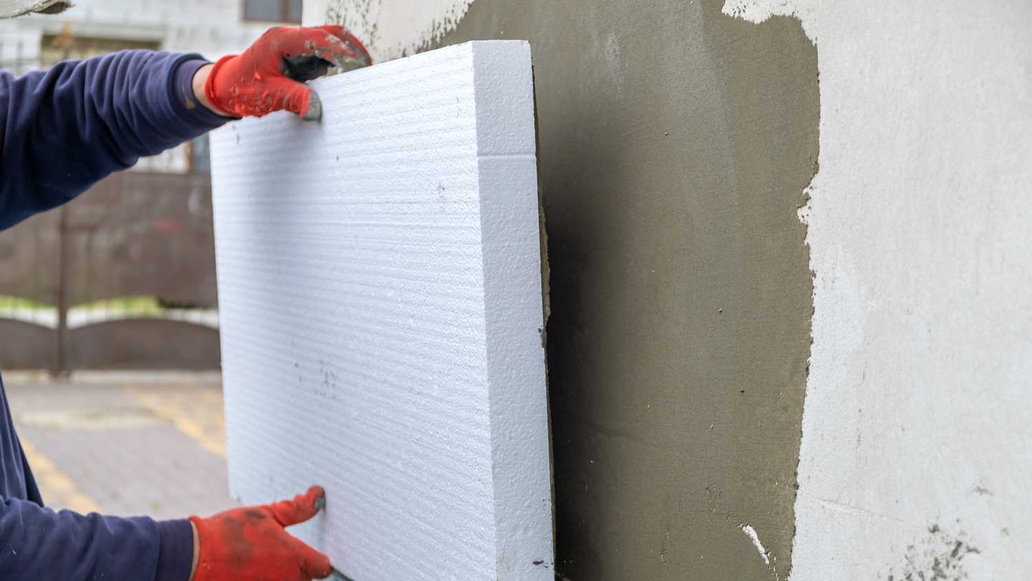 Ein Handwerker bringt Styroporplatten an die Aussenwand an zur Dämmung