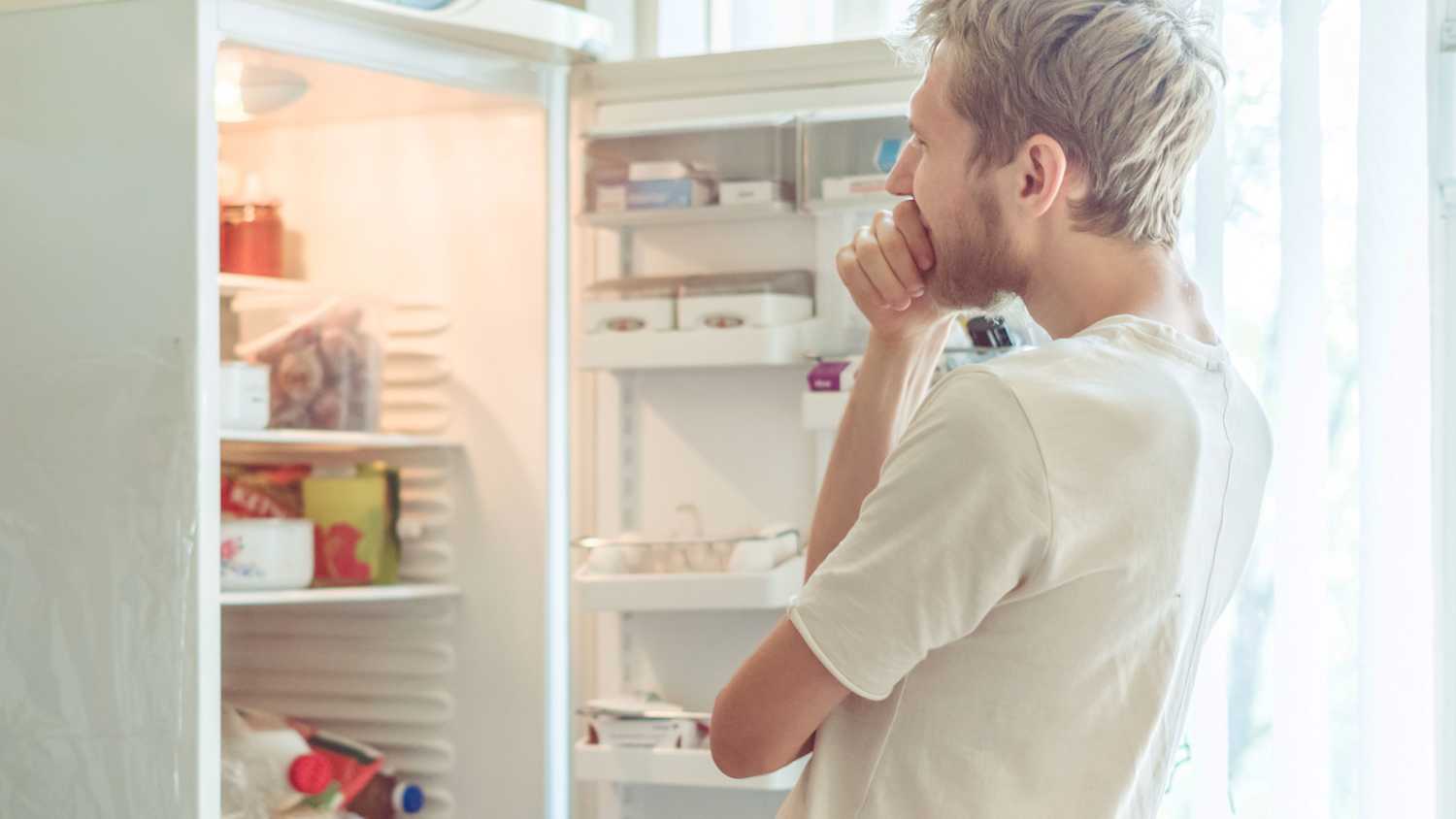 Ein Mann steht vor einem offenen Kühlschrank