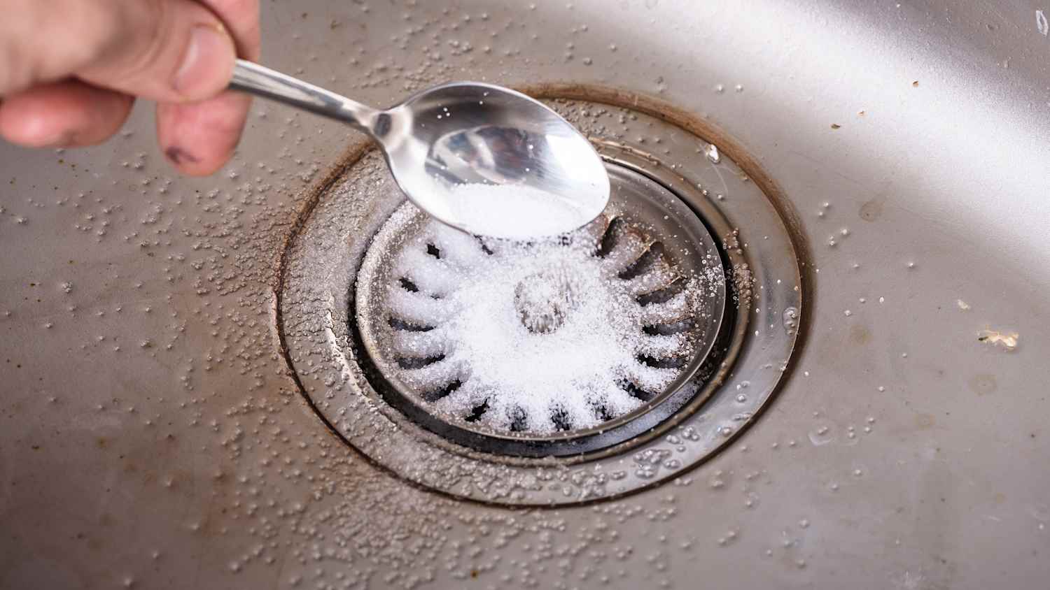 Person, die das Backpulver auf den Abfluss im Waschbecken verteilt