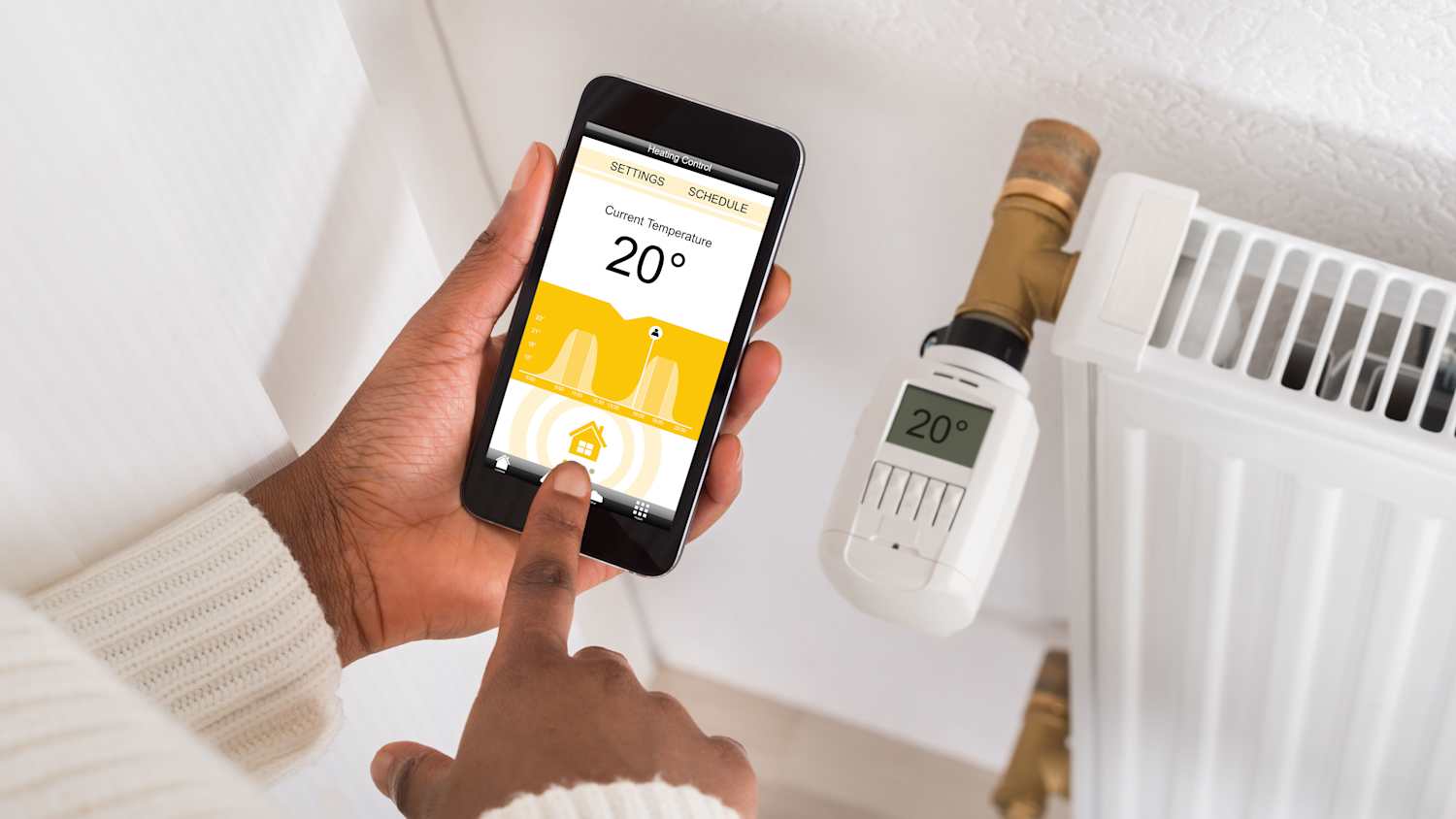 Ein Mann checkt mit seinem Smartphone die Temperatur in seinem smart-home Heizkörper