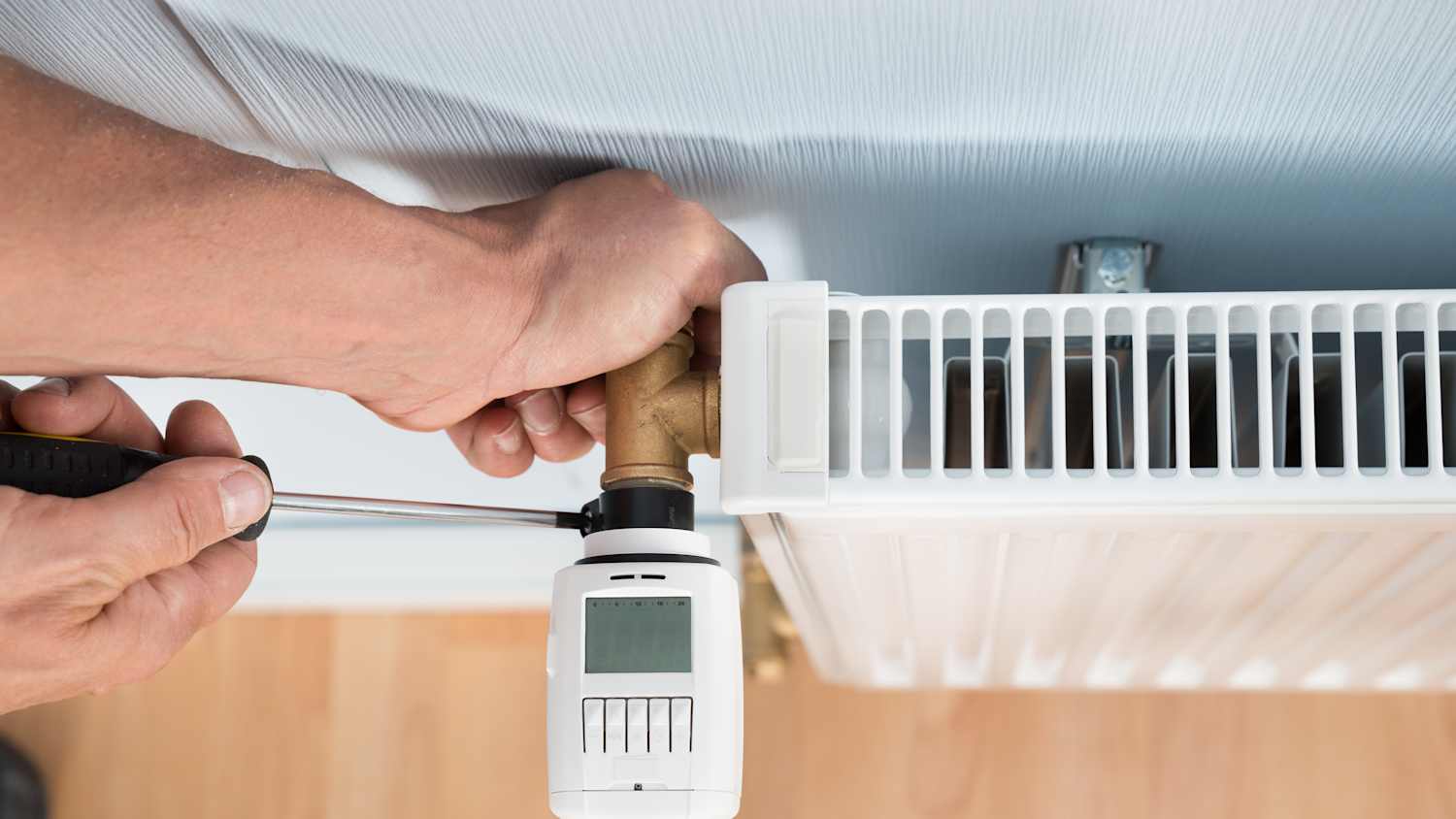 Ein Mann installiert zu Hause einen digitalen Thermostat