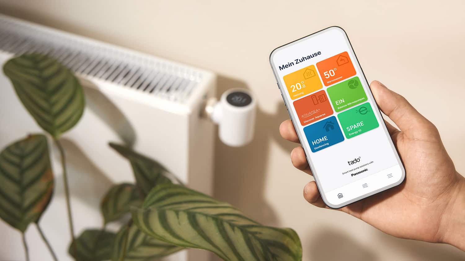 Ein Mann hält sein Handy mit der smart home App zum regeln der Temperatur  in der Hand