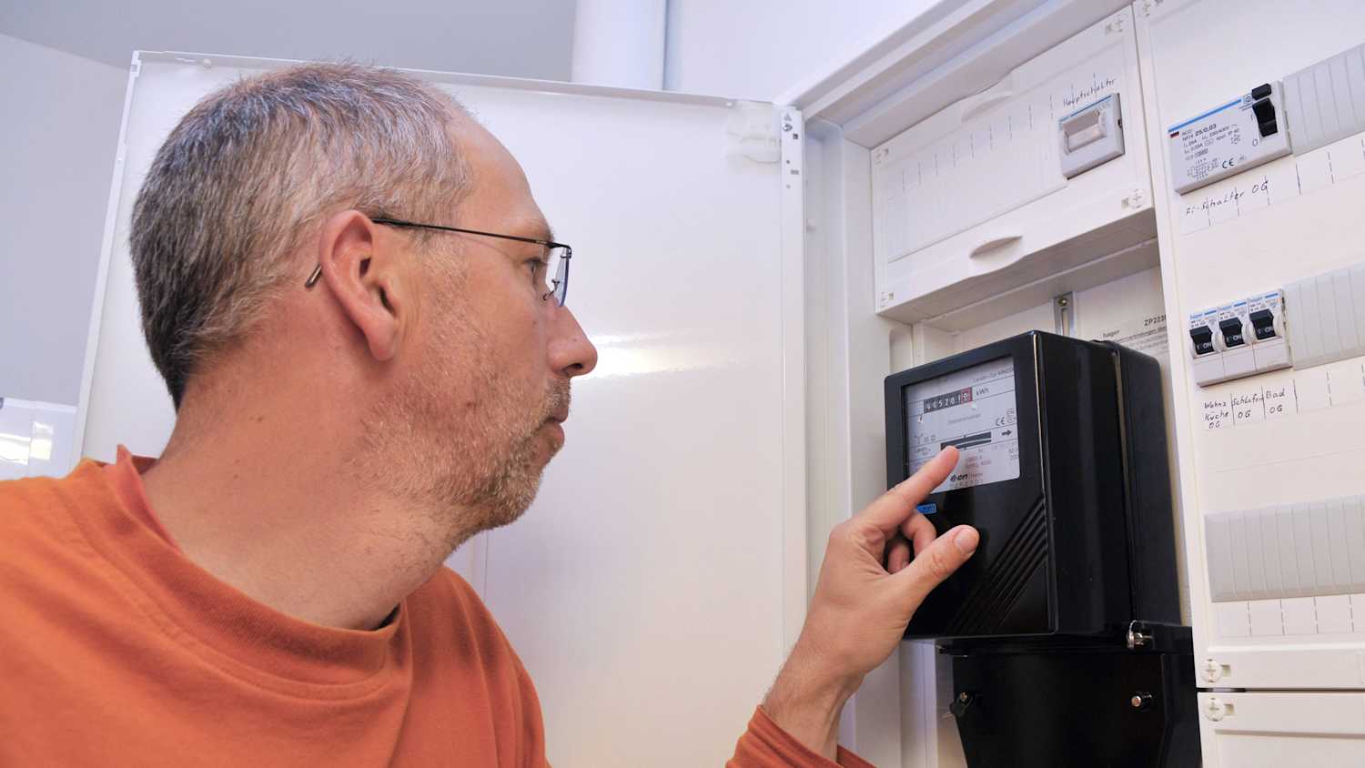 Ein Mann liest den Zählerstand an seinem Stromzähler ab