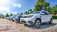 Verschiedene Dacia Modelle stehen auf dem Kiesparkplatz bei einem Autohändler im Sommer