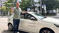 Christof Henn steht vor einem Carsharing Auto von Share Now