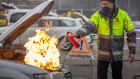 Ein Mann löscht mit dem Handfeuerlöscher einen Brand im Motorraum