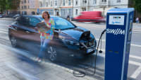 Frau lädt ihr Elektroauto an einer Ladesäule in München