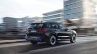 Ein neuer schwarzer BMW iX3 von hinten, während der Fahrt durch die Stadt