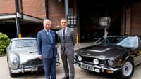 Prinz Charles und Daniel Craig stehen vor 2 Aston Martin