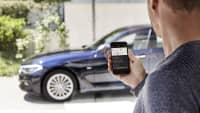 Mann verbindet sein Smartphone mit parkendem schwarzen BMW