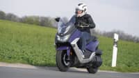 Ein Motorroller Maxsym 400 fährt auf einer Straße