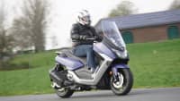 Ein Motorroller Maxsym 400 fährt auf einer Straße, seitlich zu sehen