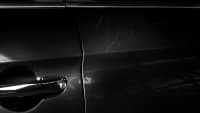 Einige Kratzer im Lack auf der Türe eines schwarzen Autos