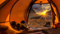 Blick durch ein orangenes Zelt in den Sonnenuntergang