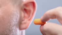Ein Mann hält einen Ohrstöpsel an sein Ohr.