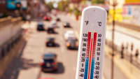 Hitze - ein Thermometer zeigt 40 Grad im Close Up im Hintergrund eine befahrene Stadtstrasse im Sommer