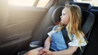 Mädchen sitzt angeschnallt im Kindersitz im Auto