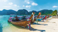 Thailändische Boote mit Bunten Stoffen am Bug, liegen an einem Strand