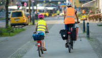Elternteil fährt mit Kind auf dem Gehweg Fahrrad