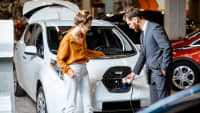 Ein Autoverkäufer berät eine Frau beim Kauf eines Elektroautos