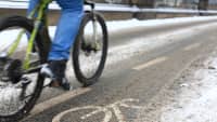 Radfahrer fährt auf verschneitem Radweg