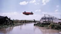 Ein Auto fliegt Kopf über in der Luft über einen Fluss