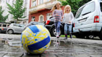 Zwei Mädchen laufen beim Spiel mit einem Ball über eine Straße