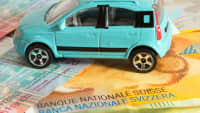 Schweizer Banknoten und ein Spielzeugauto liegen auf dem Tsich
